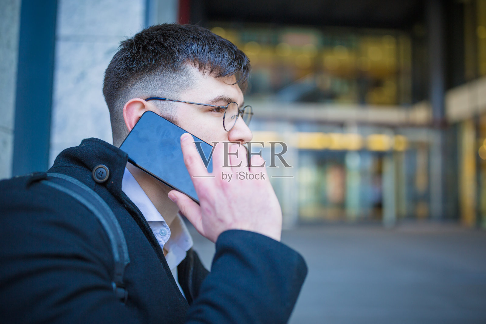 年轻时髦的建筑师，正在用手机，坐在办公大楼前照片摄影图片