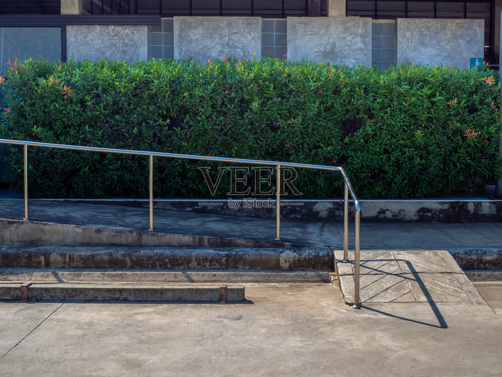 破旧的轮椅坡道上有金属棒，旁边是空的停车场照片摄影图片