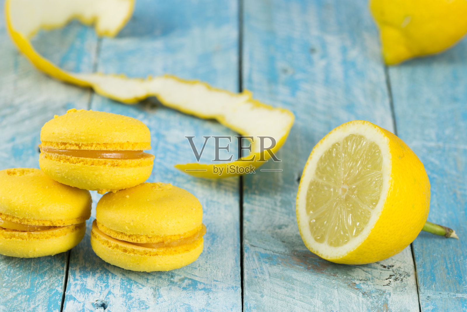 黄色的柠檬马卡龙，有天然的柠檬和蓝色的木制背景照片摄影图片