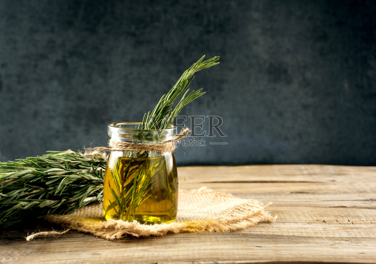 迷迭香油。迷迭香精油瓶，玻璃瓶和植物迷迭香枝与花在木材背景上。照片摄影图片