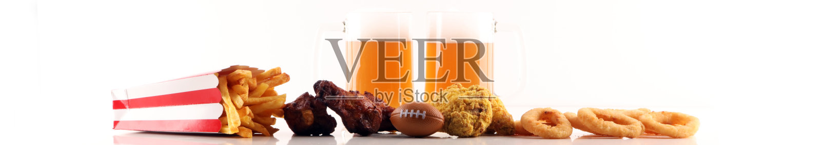 桌上放着薯条、咸味小吃、足球和啤酒。非常适合保龄球比赛项目。照片摄影图片