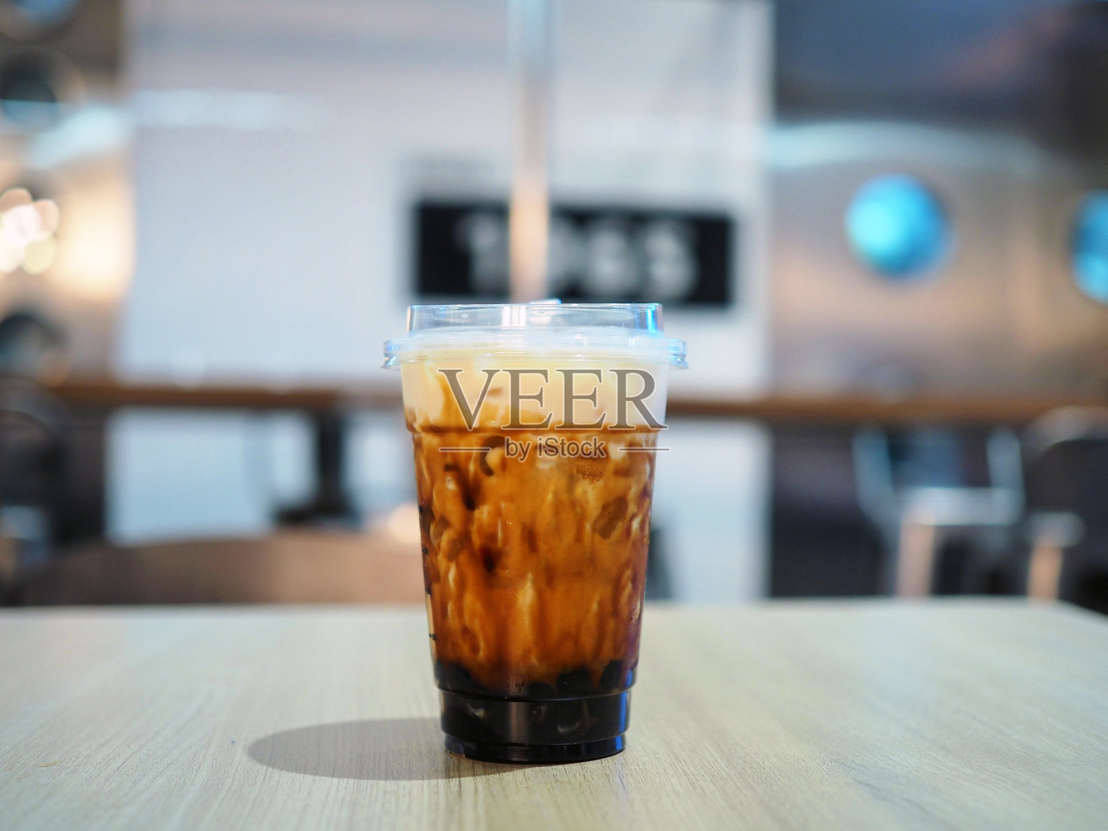 一杯新鲜的冰奶茶，桌上放着珍珠奶茶和红糖。照片摄影图片