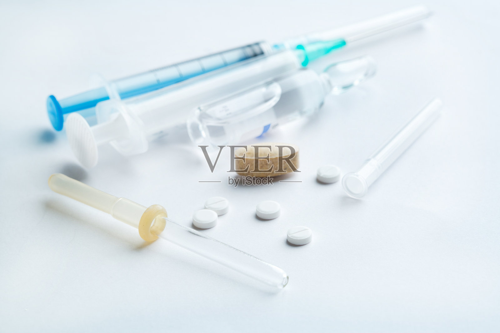 药丸和注射器，白色木质背景。治疗的概念。照片摄影图片