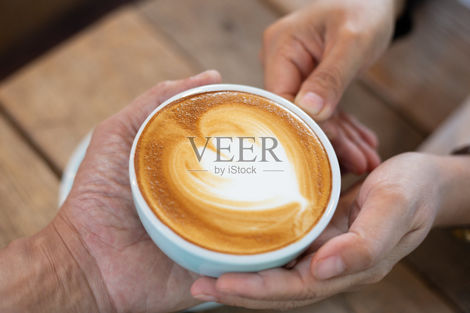 手女人把拿铁咖啡热咖啡放在木桌上。咖啡师的艺术概念。照片摄影图片