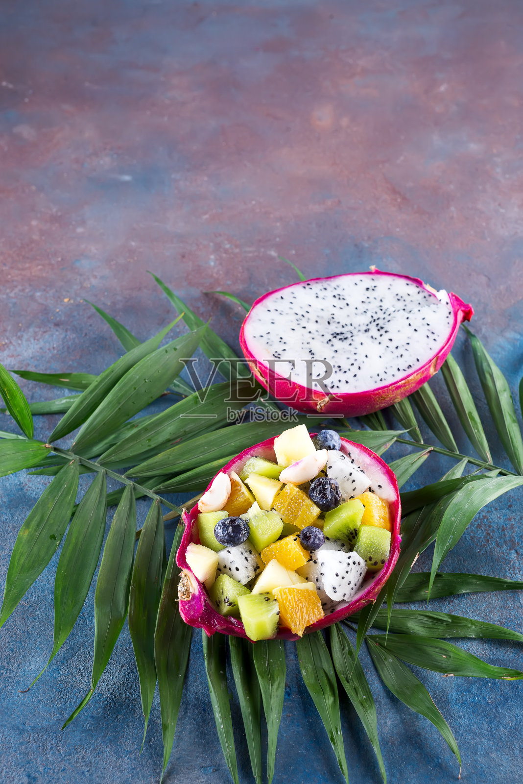 异国情调的水果沙拉，半火龙果在棕榈叶上石质背景，复制空间照片摄影图片
