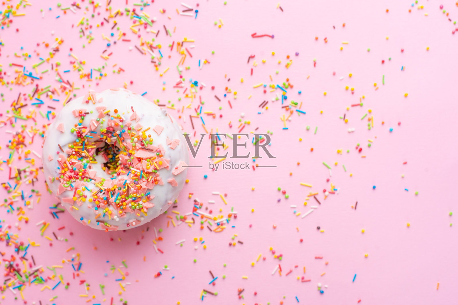 粉粉色背景上涂着糖霜的甜甜圈。可爱的甜甜圈。平的。横幅照片摄影图片