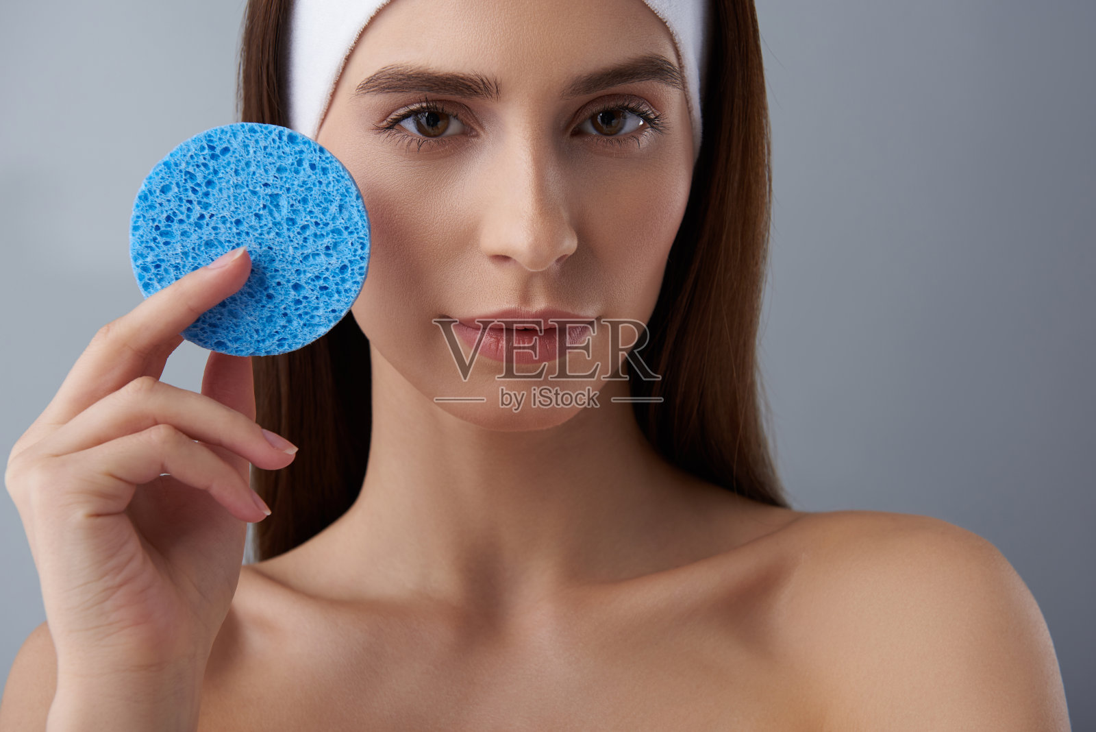 美丽的年轻女士与完美的皮肤拿着蓝色海绵照片摄影图片