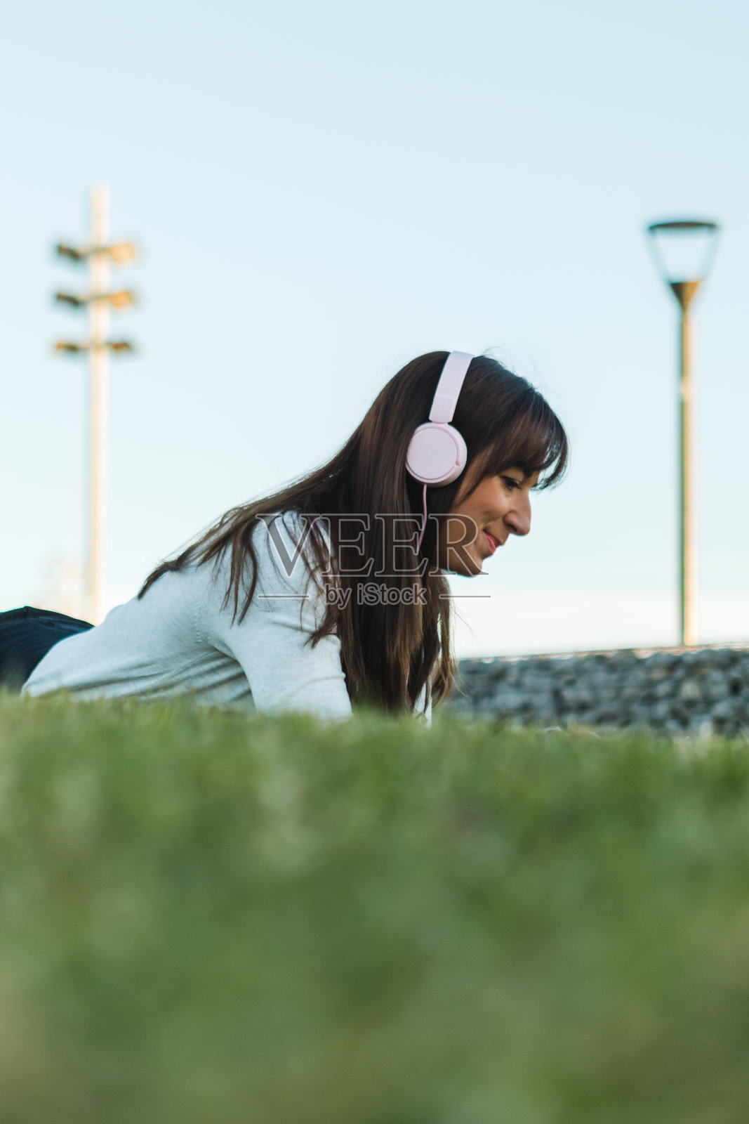 放松的学生学习语言视频教程在线耳机和笔记本电脑躺在草地上的公园照片摄影图片