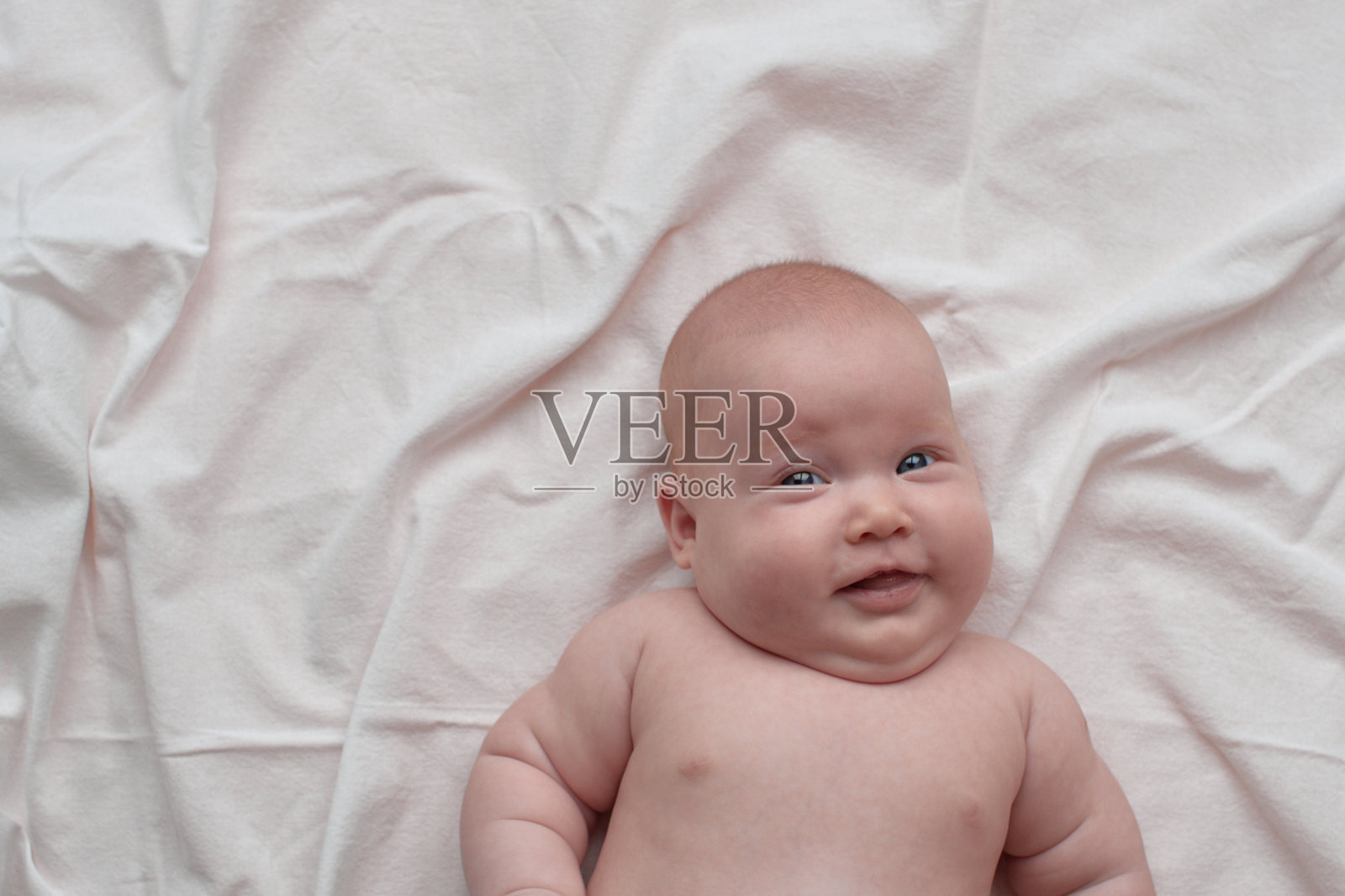 开心微笑的婴儿躺着，看着画面。照片摄影图片