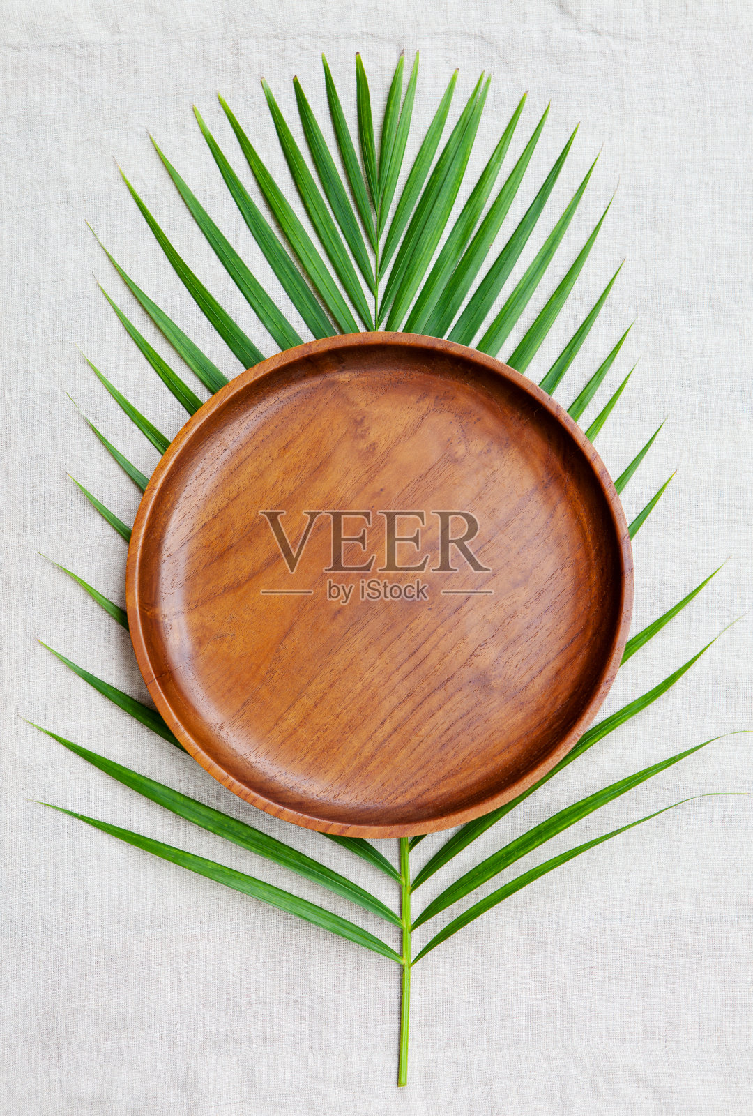 木制板与棕榈叶在天然亚麻纺织背景。副本的空间。俯视图照片摄影图片