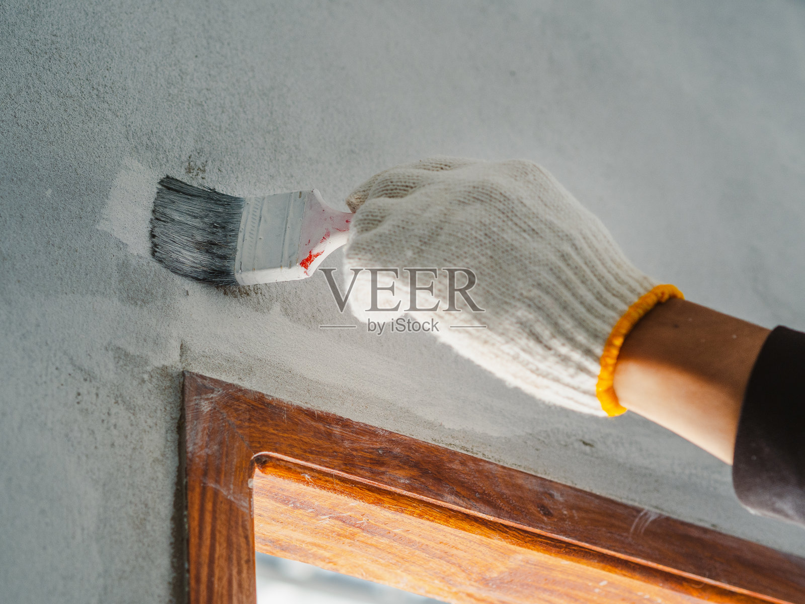 工人用滚筒和刷子刷墙的手的特写。房屋建筑的概念。照片摄影图片