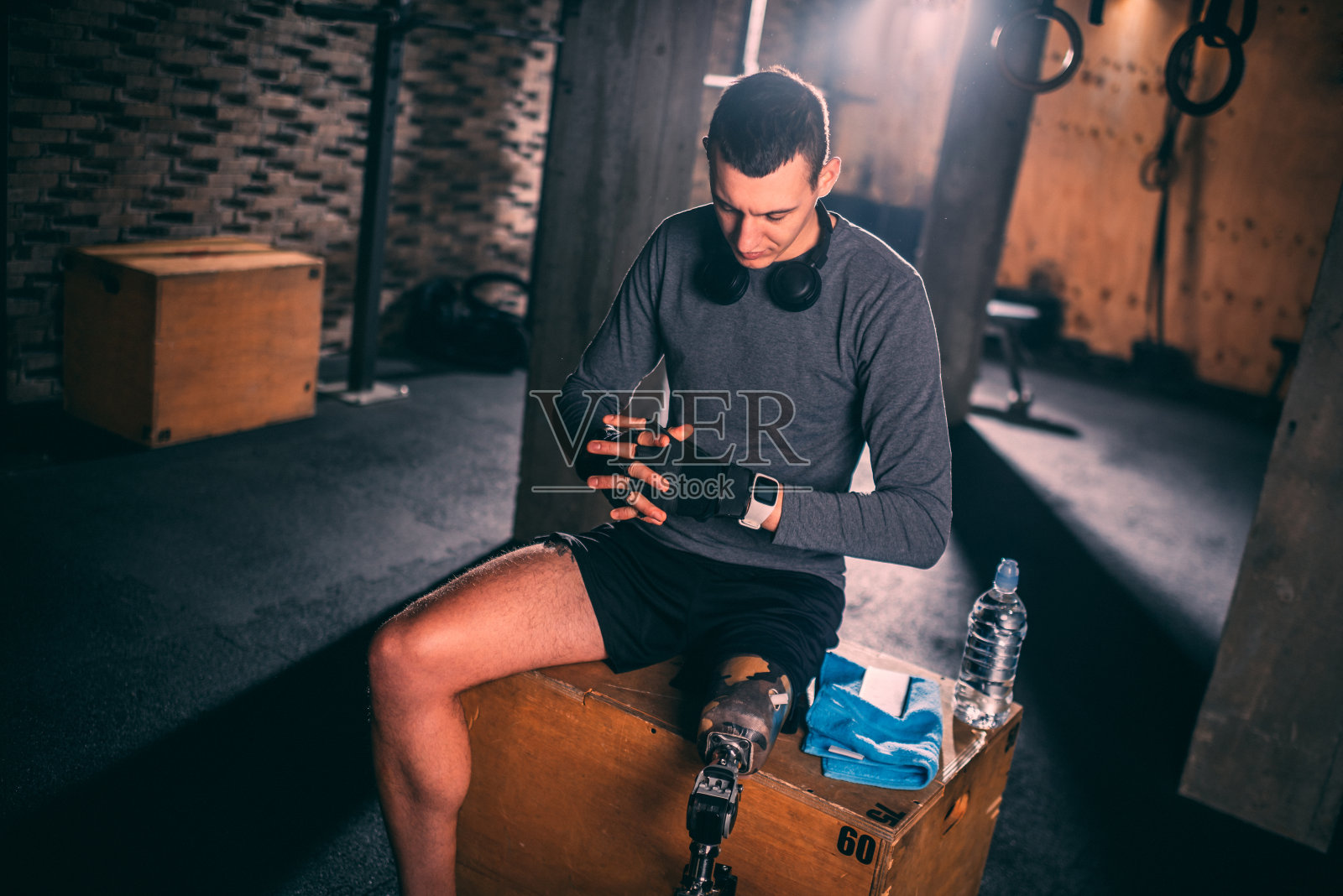 年轻的适应性运动员在体育馆的健身箱上调整他的训练手套准备训练照片摄影图片