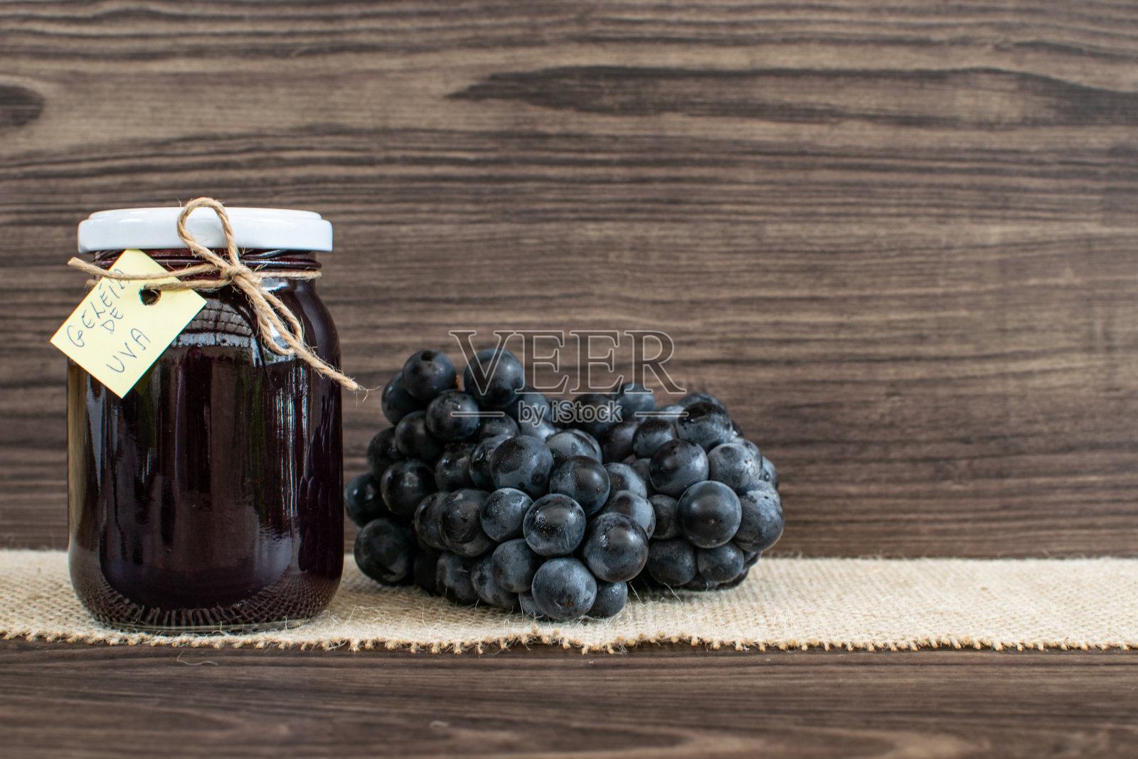 熟透的葡萄和自制的果酱放在锅里，面包放在木桌上，有选择性的集中。照片摄影图片