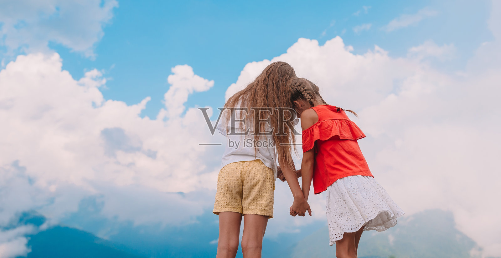 美丽快乐的小女孩们在群山的背景雾中照片摄影图片