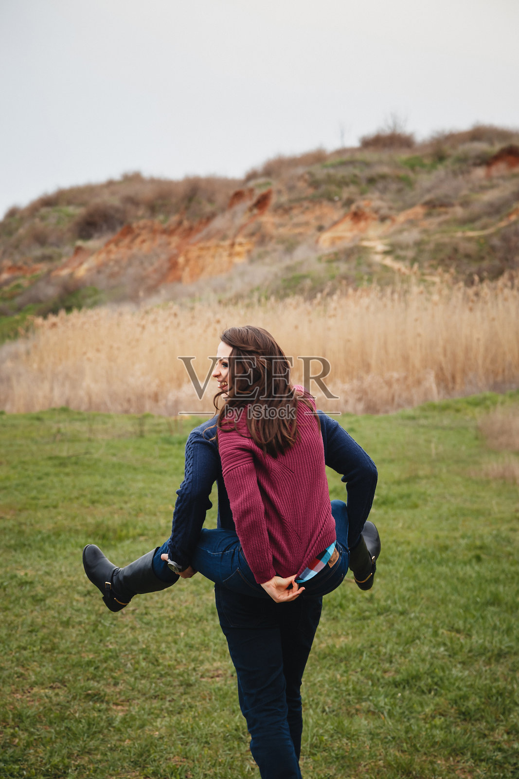 一对可爱的年轻夫妇在开玩笑，在绿色的田野中间骑着马。美好的日子，幸福的友谊，节日的概念照片摄影图片