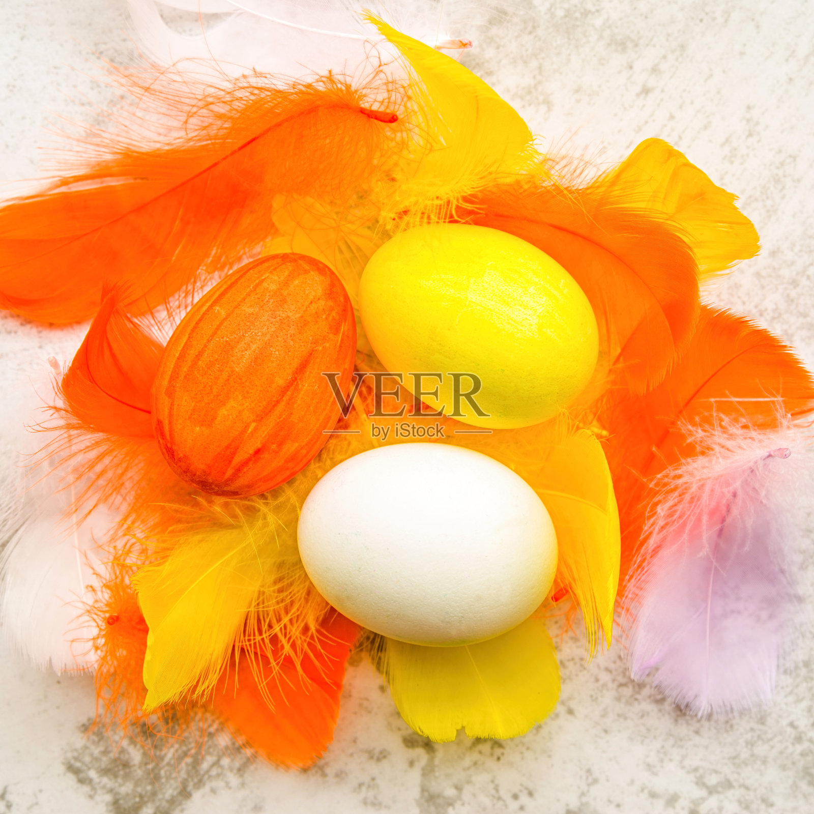 复活节彩蛋在彩色的羽毛上，在白色大理石的背景平躺俯视图照片摄影图片