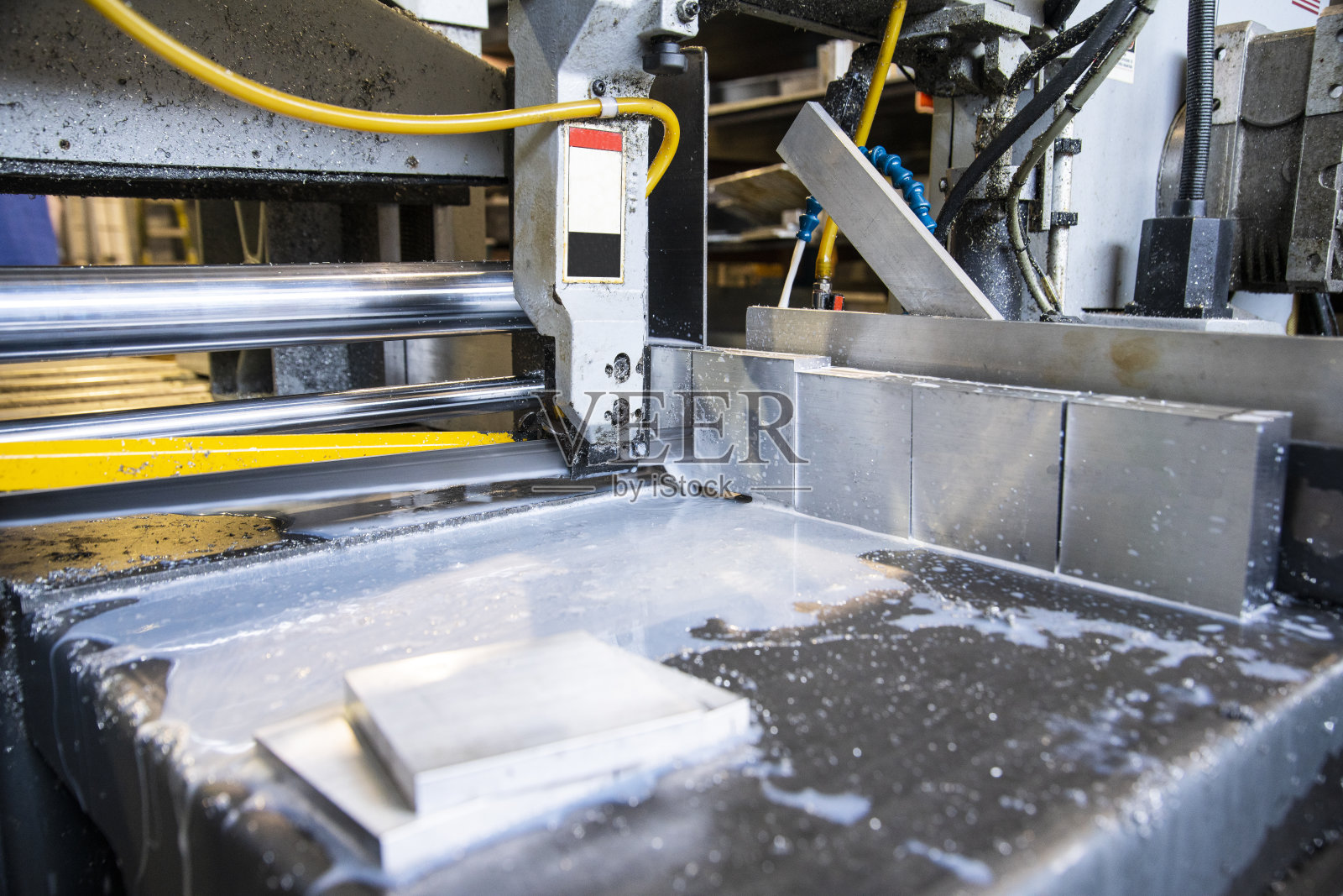 在机械车间中运行的自动金属切割锯。照片摄影图片