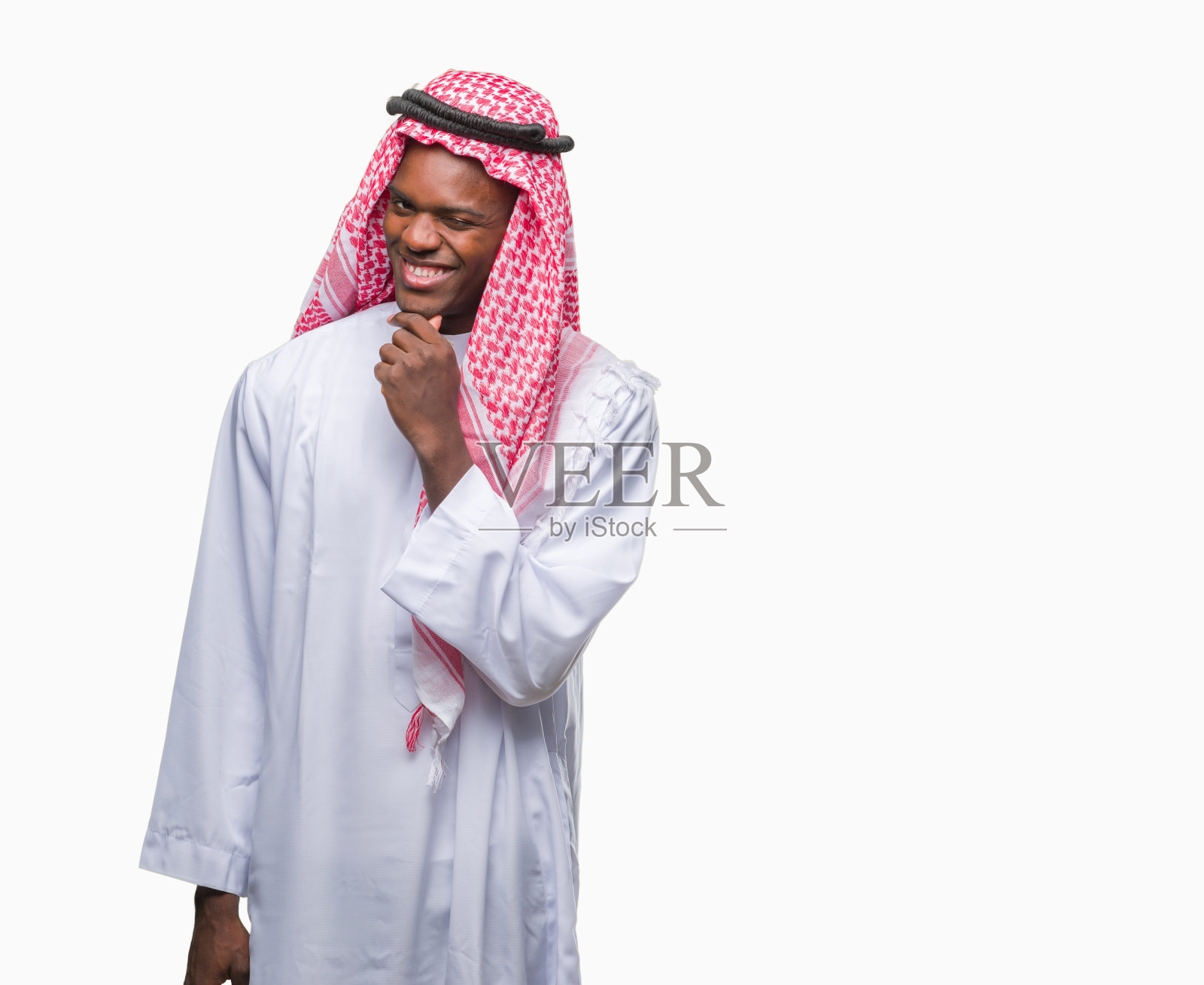 年轻的阿拉伯裔非洲人穿着传统的keffiyeh在孤立的背景下看起来自信地看着镜头，双臂交叉，手举在下巴上。积极的思考。照片摄影图片