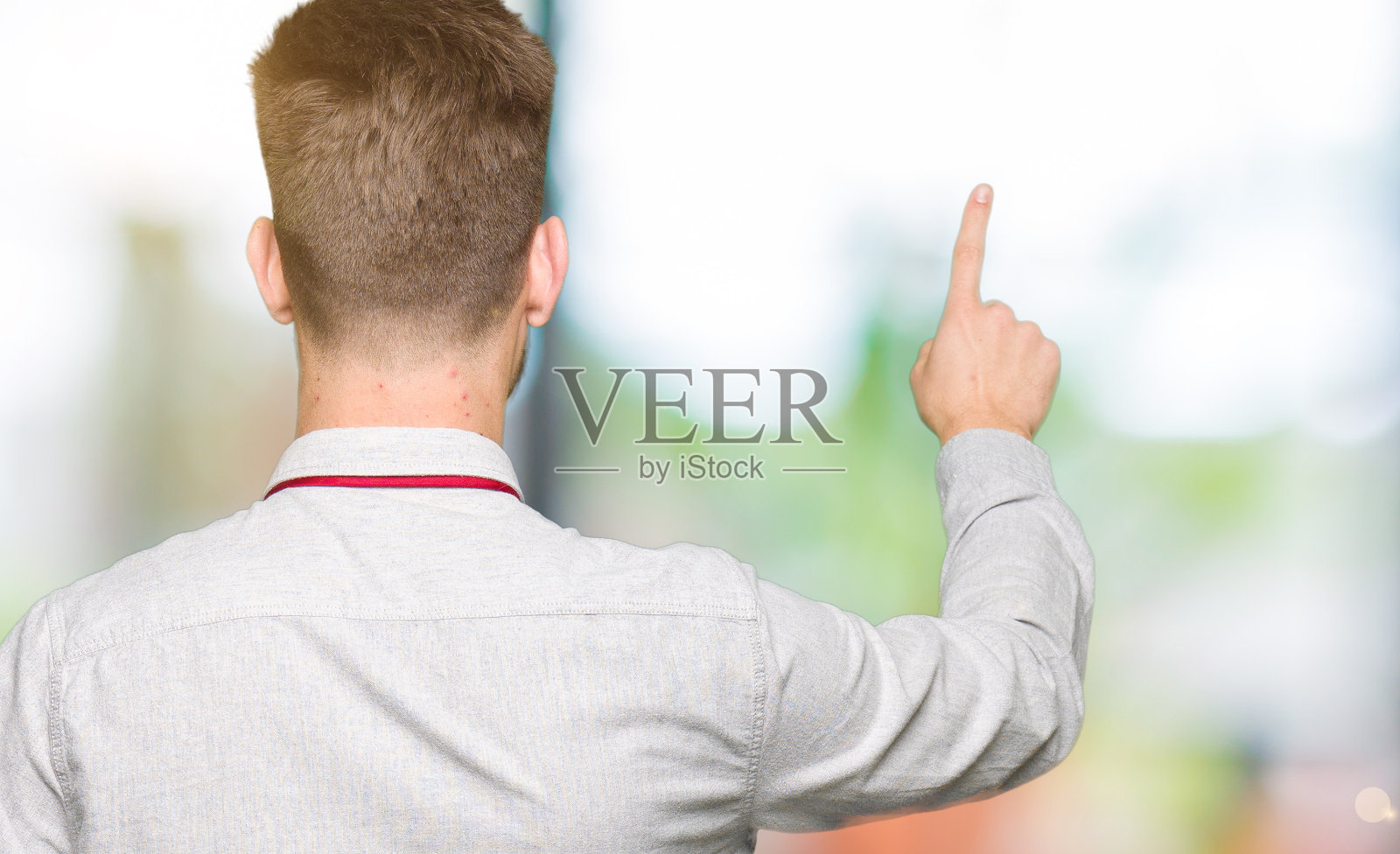 年轻英俊的商人摆出向后指着手指的手照片摄影图片