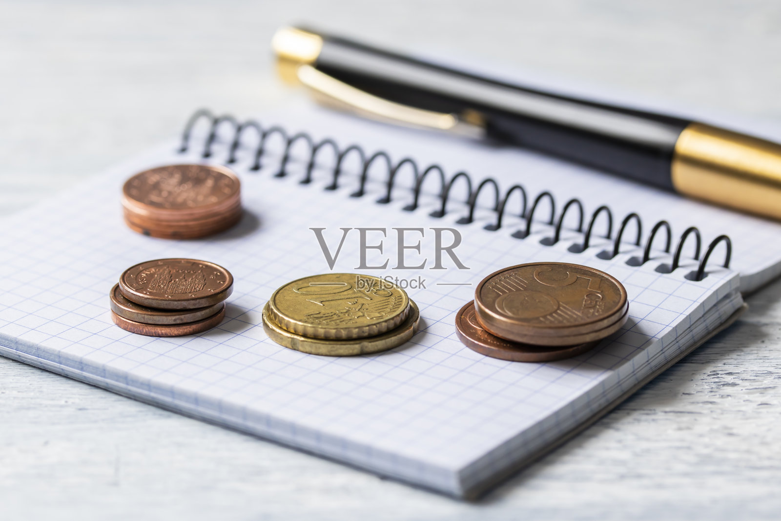 商业、金融或投资概念。硬币，支票簿或笔记本和钢笔。白色木制背景。照片摄影图片