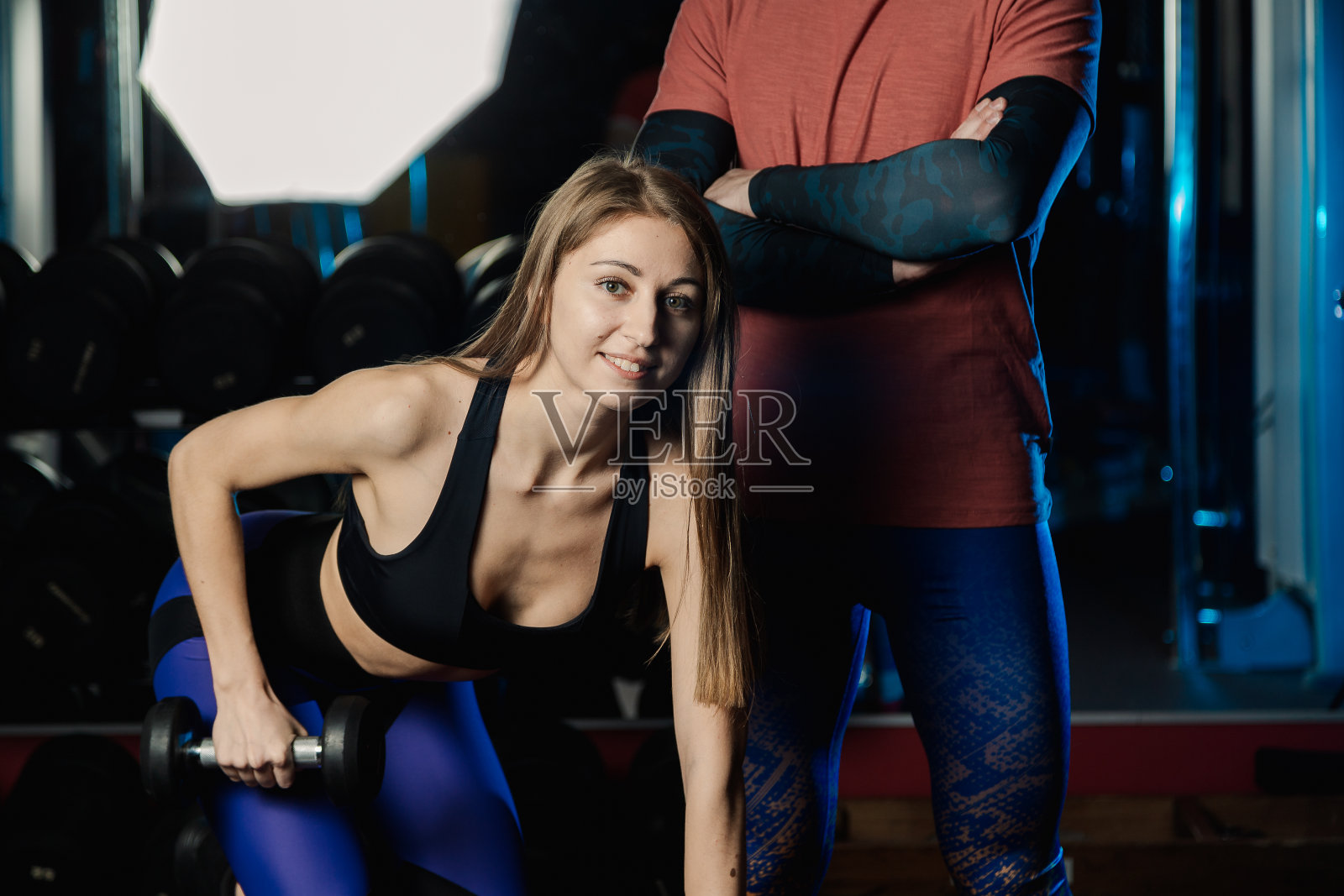 活泼漂亮的健身模特和运动员在健身房用哑铃训练照片摄影图片