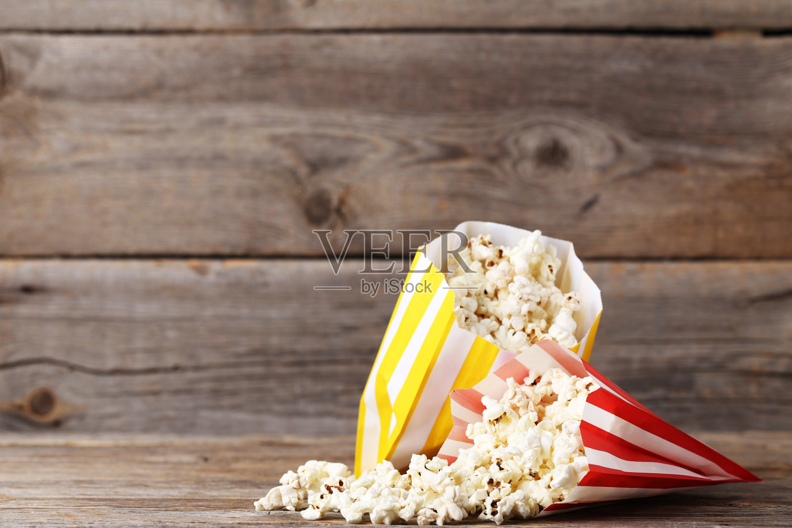 装在纸袋里的爆米花放在灰色的木桌上照片摄影图片