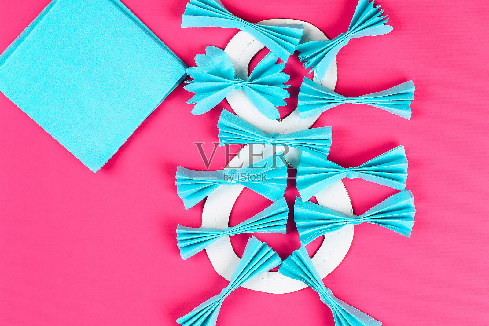 Diy八做纸板装饰人造花做蓝色纸巾餐巾粉色背景。照片摄影图片