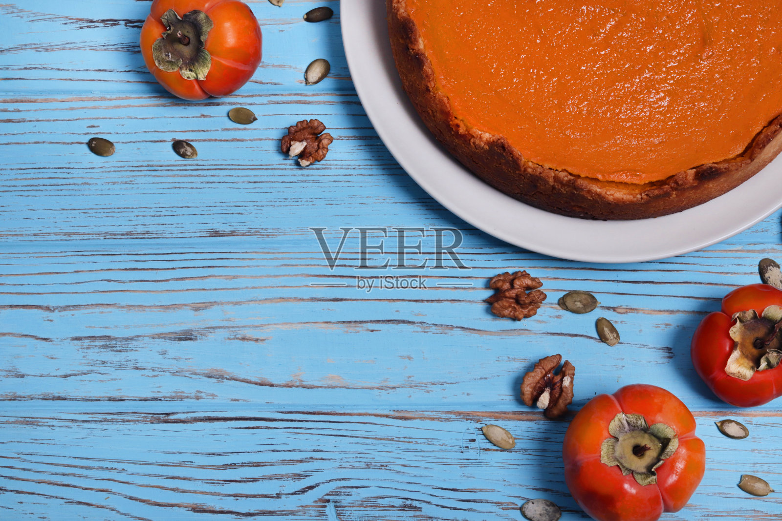 美丽的南瓜派与坚果在一个蓝色的木制背景。圣诞蛋糕。文本。前视图。照片摄影图片