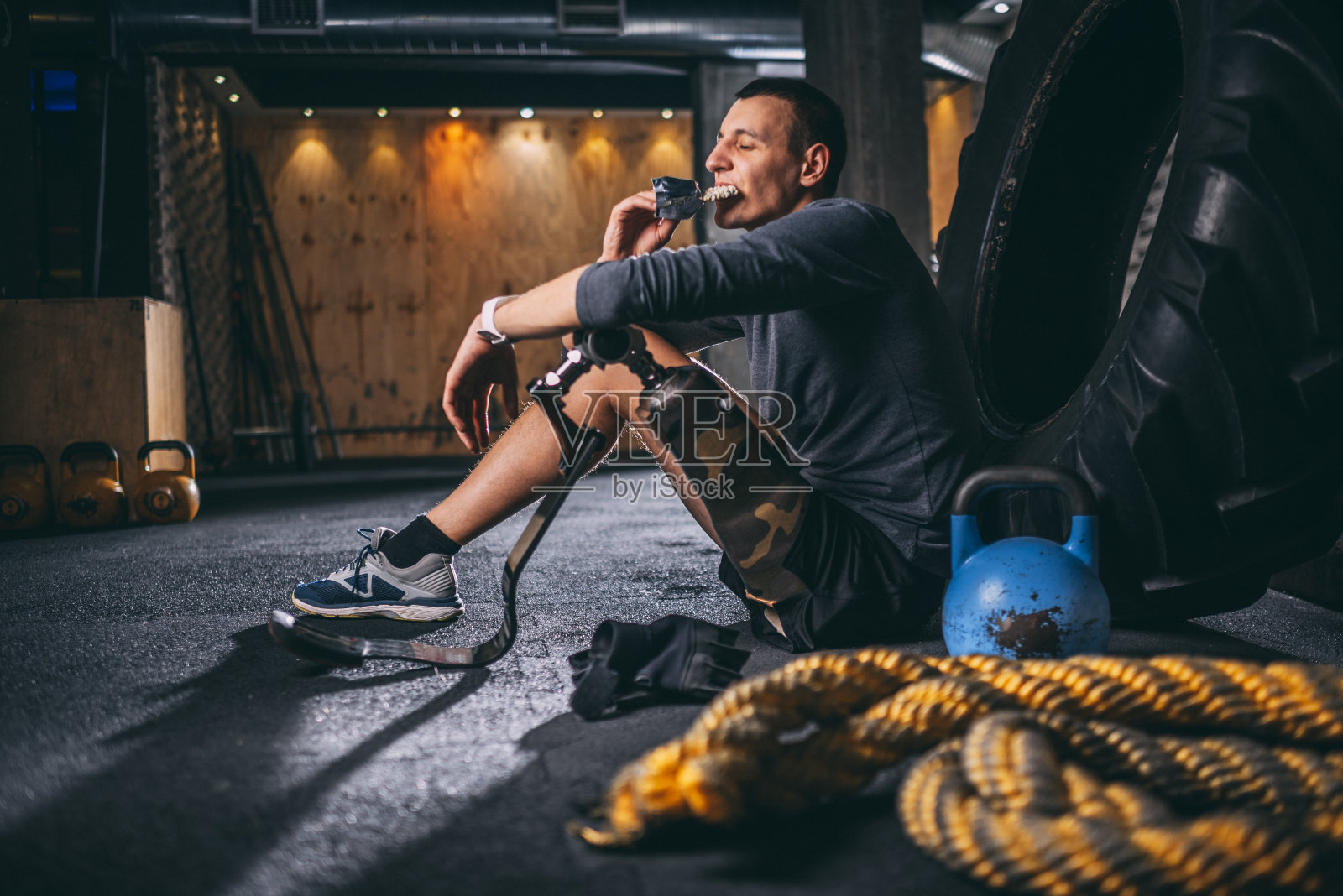 年轻的适应性运动员在健身房里休息时吃能量蛋白棒照片摄影图片