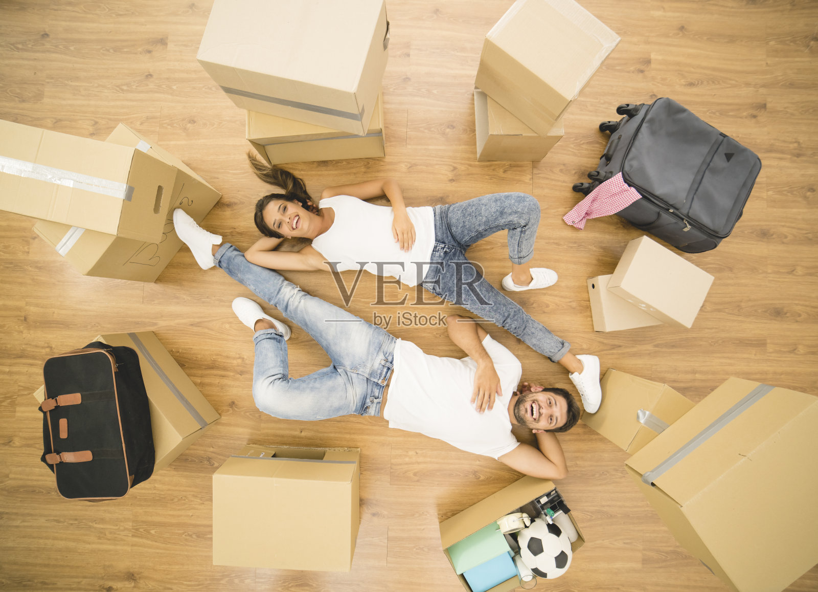 那对幸福的夫妇躺在镶木地板上。从上面的观点照片摄影图片