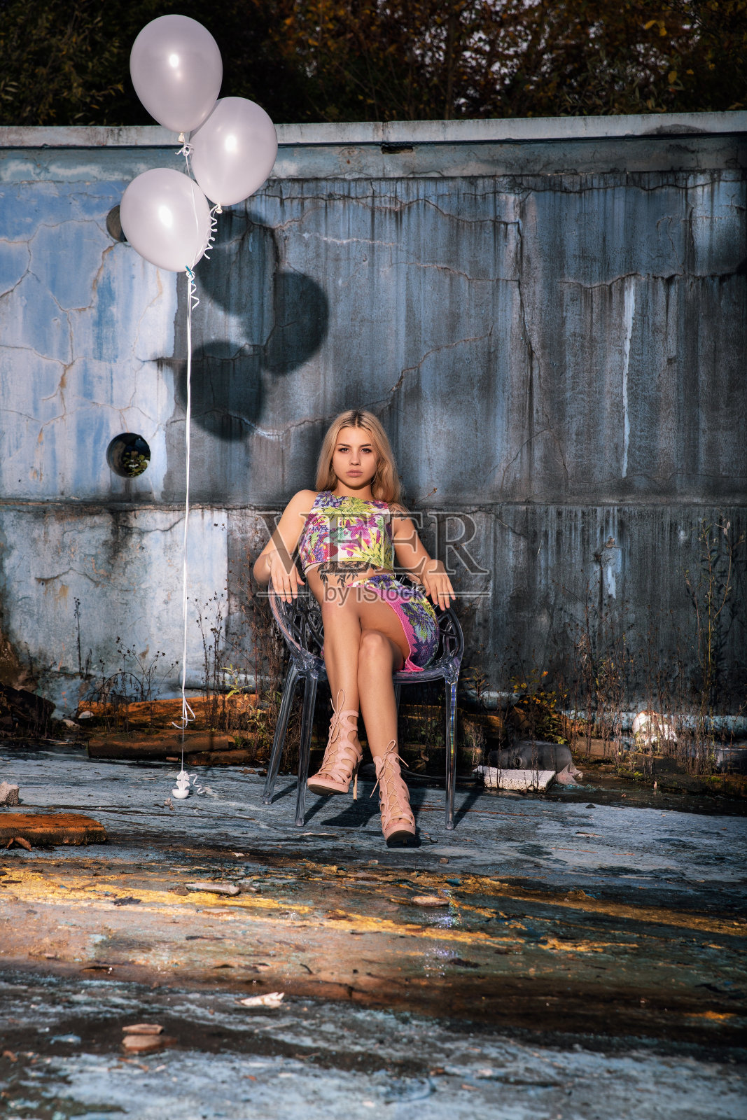 年轻时尚女性坐在废弃的泳池里，手里拿着气球照片摄影图片