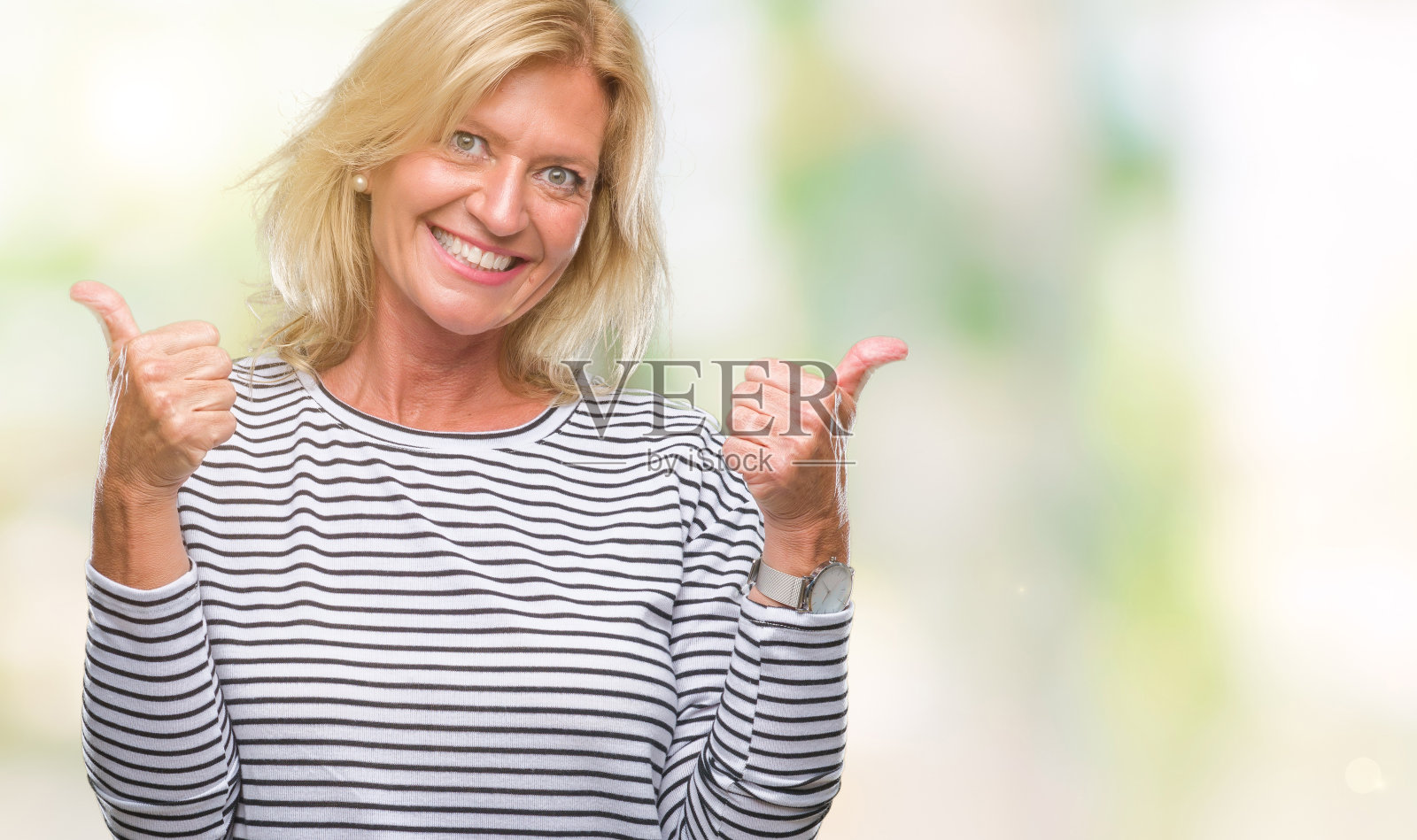 中年金发女子在孤立的背景成功手势做积极的手势，大拇指向上微笑和快乐。带着愉悦的表情看着镜头，胜利者的姿态。照片摄影图片