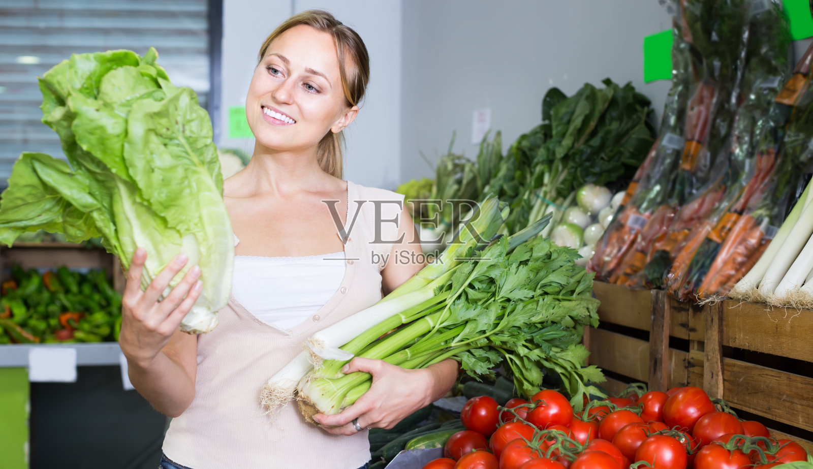 微笑的年轻女顾客拿着新鲜芹菜和韭菜照片摄影图片