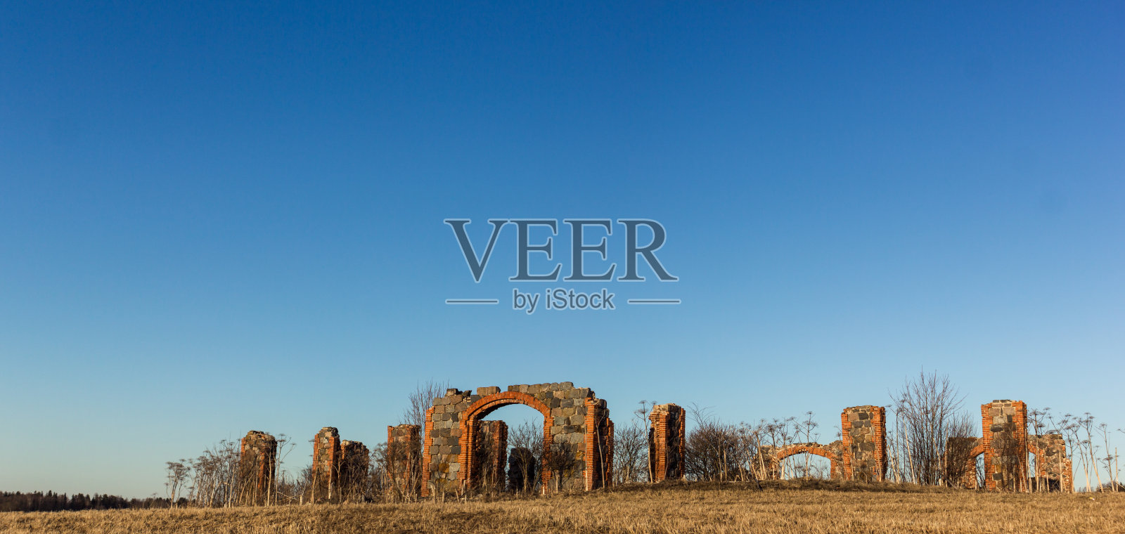 一幢古老建筑的石柱遗迹，在阳光明媚的春日田野中央照片摄影图片