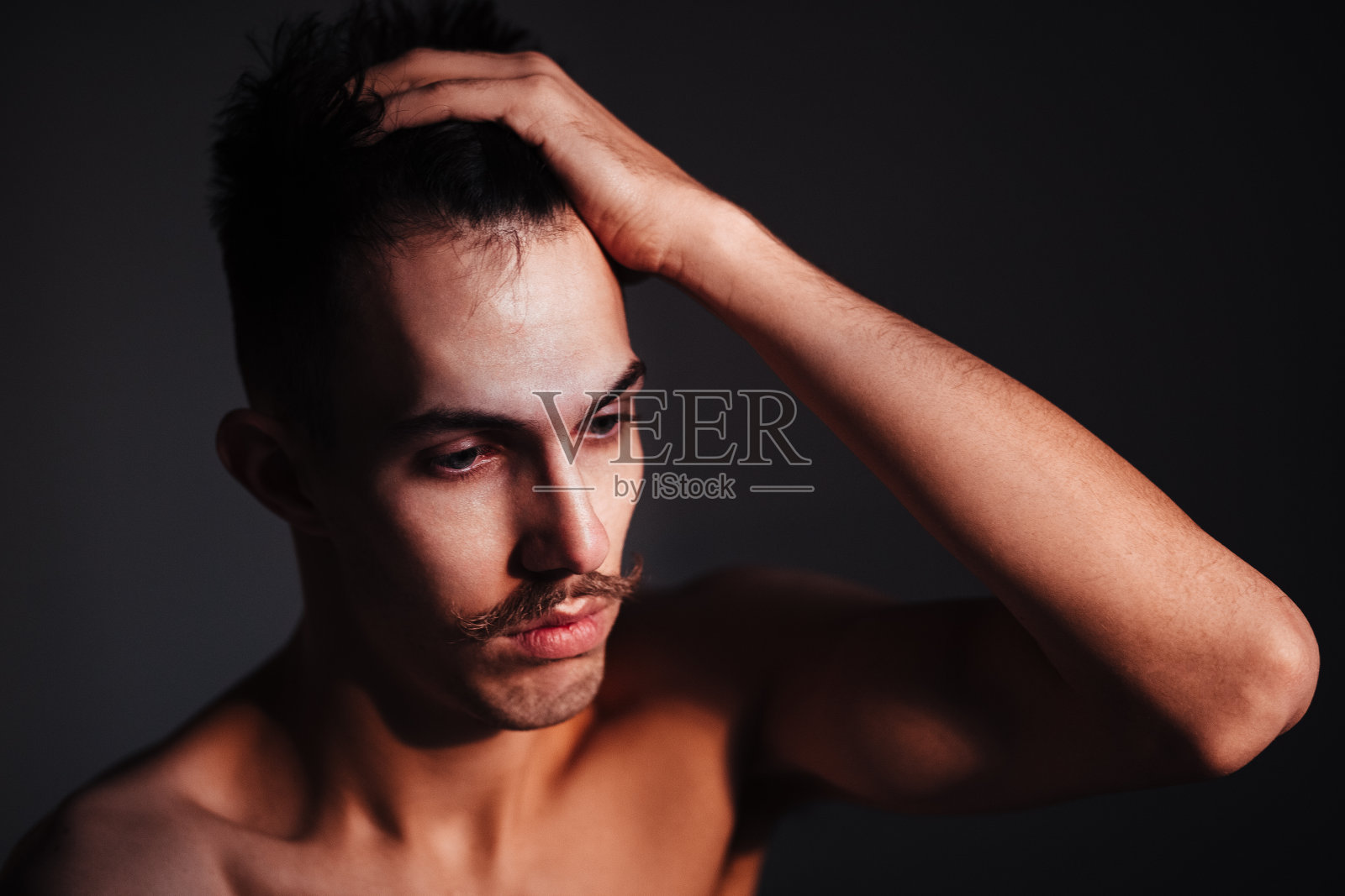 在窗边思考的留着胡须的年轻赤膊男子照片摄影图片