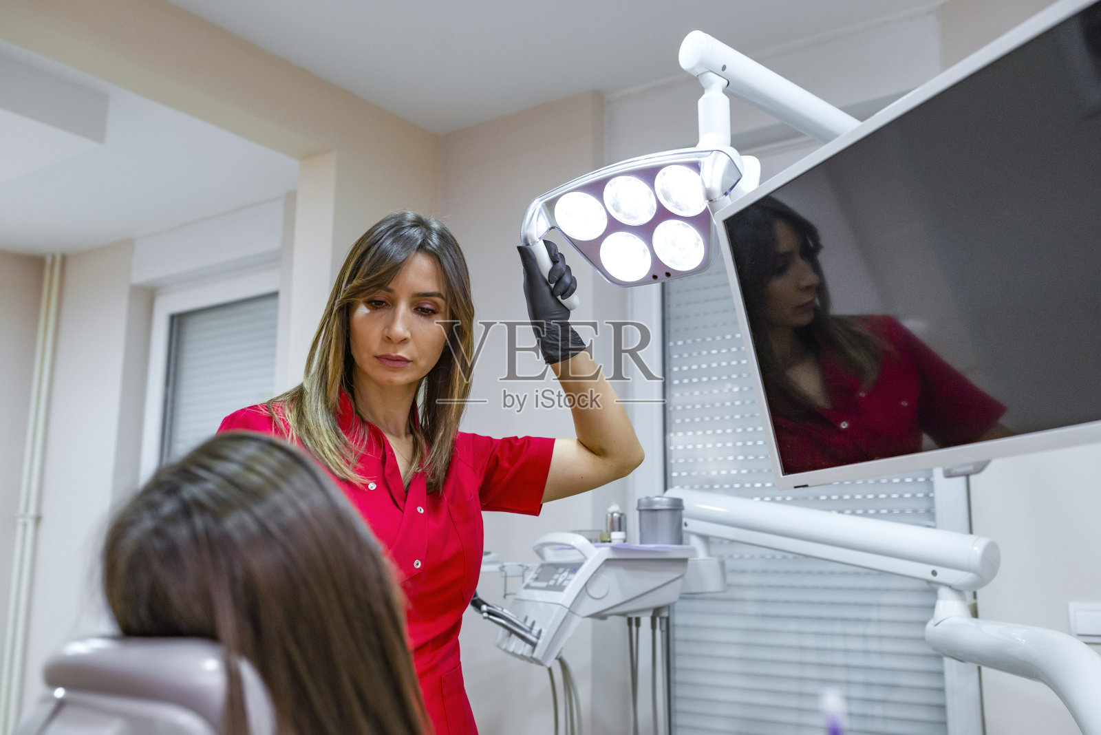 牙医在牙科椅上治疗牙齿女孩。照片摄影图片