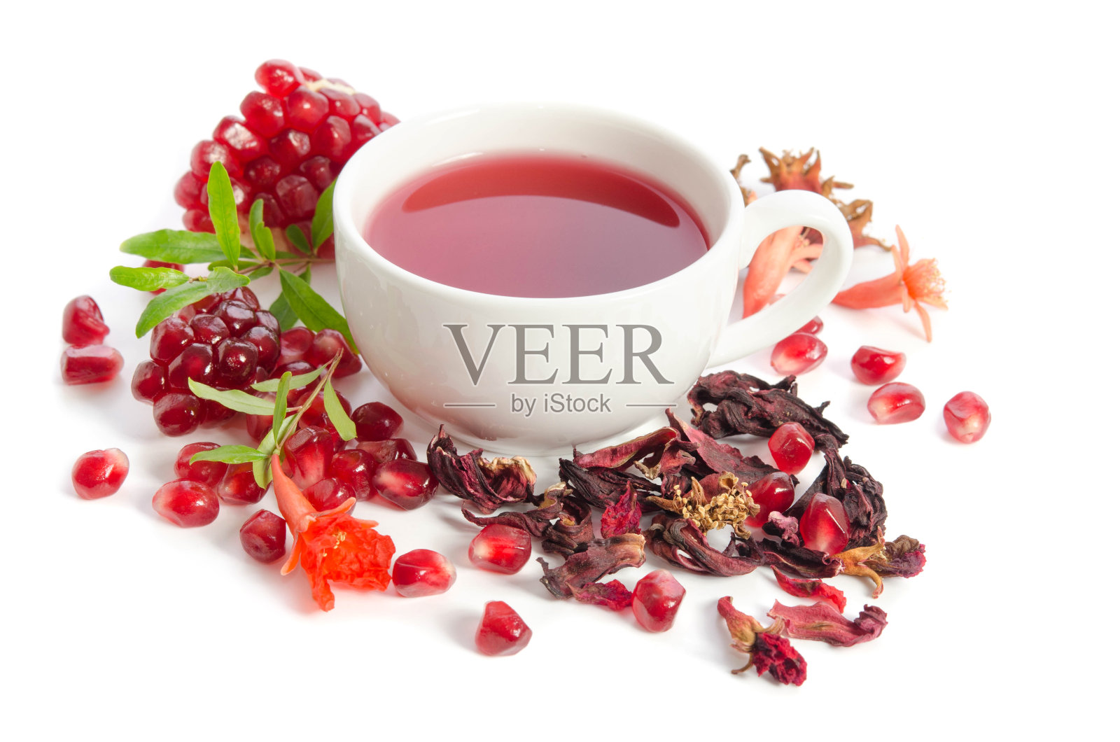部分石榴有石榴籽和石榴叶，花，干茶和满杯茶孤立在白色的背景照片摄影图片
