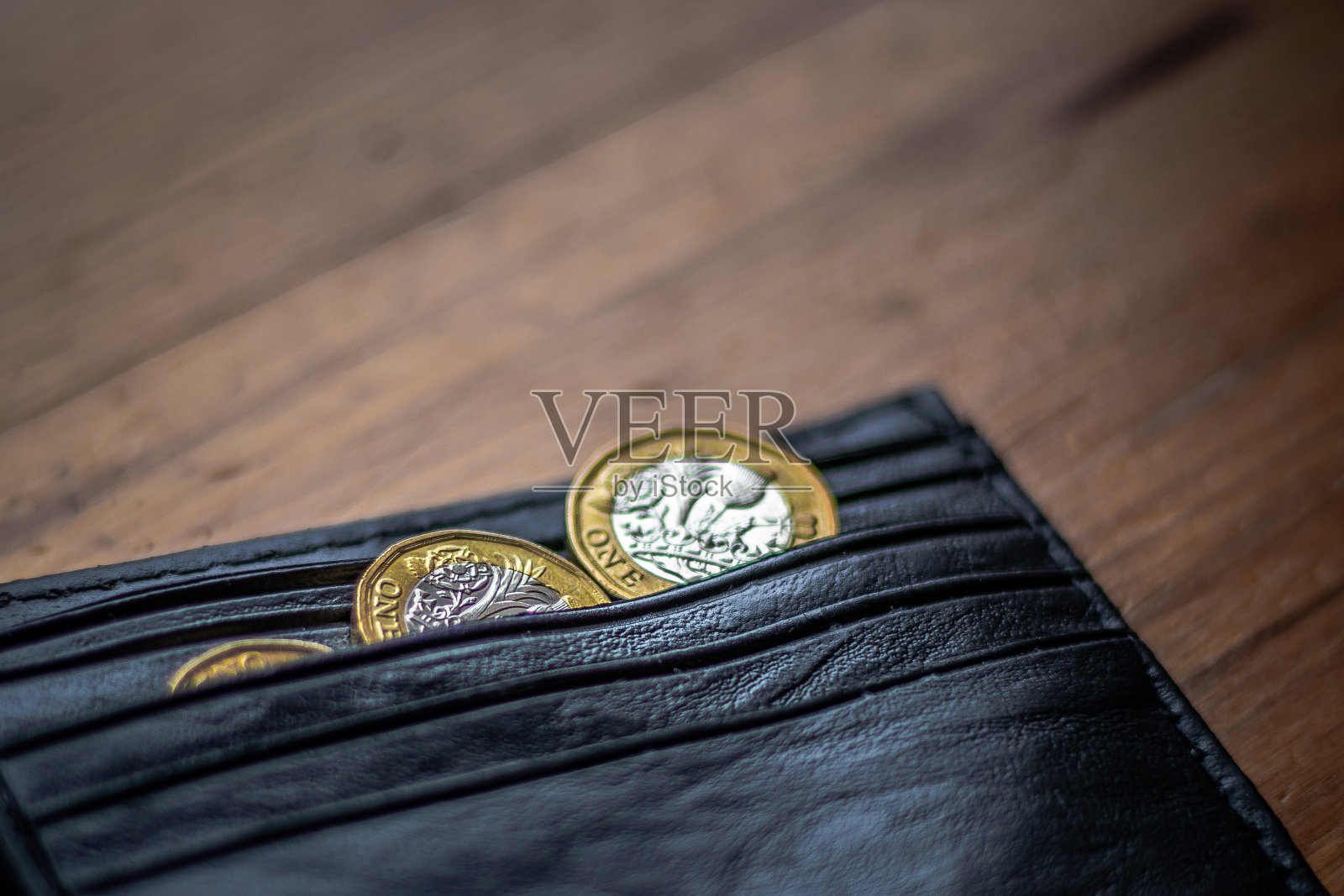 新英国英镑英镑硬币随意放置在黑色钱包上的木制表面。财富，金钱，现金，零钱。照片摄影图片