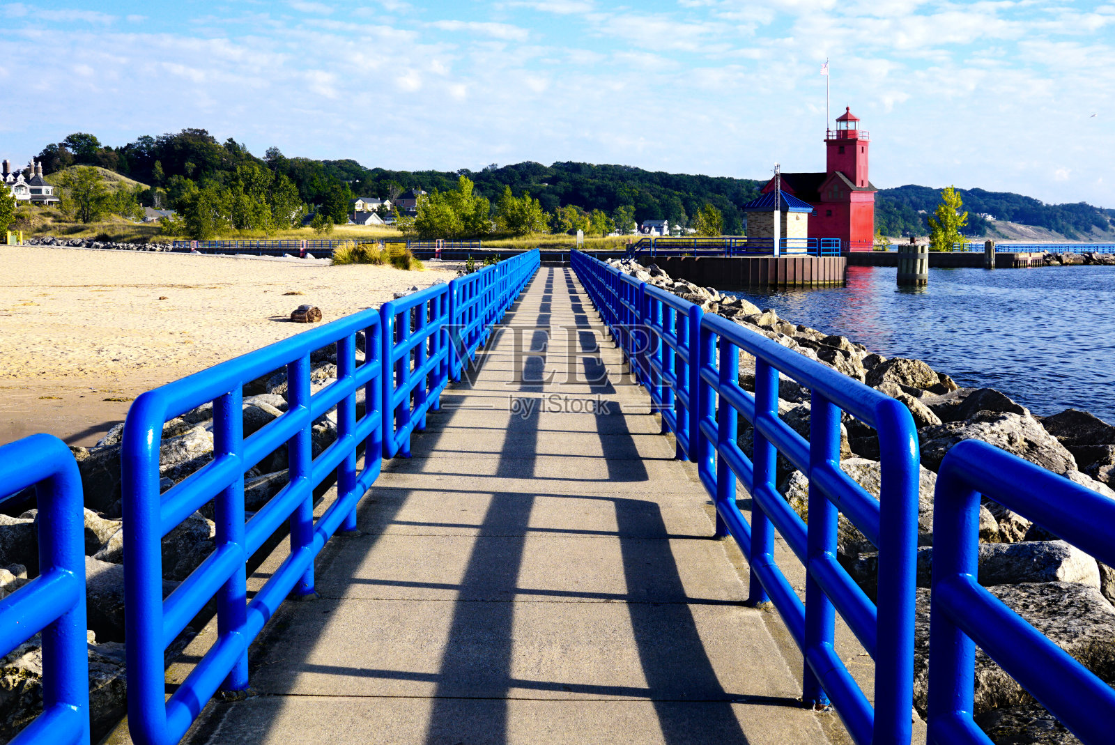 有亮蓝色栅栏的码头。密歇根湖上的大红色灯塔照片摄影图片