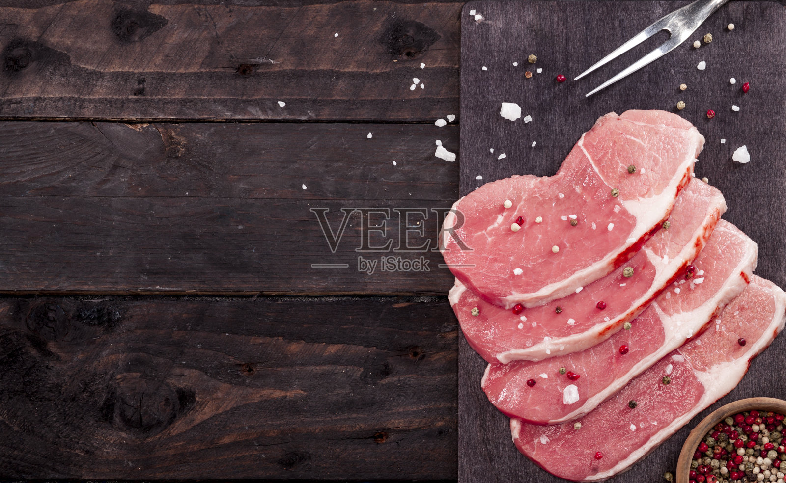 在切菜板上放上生牛排和香料。照片摄影图片