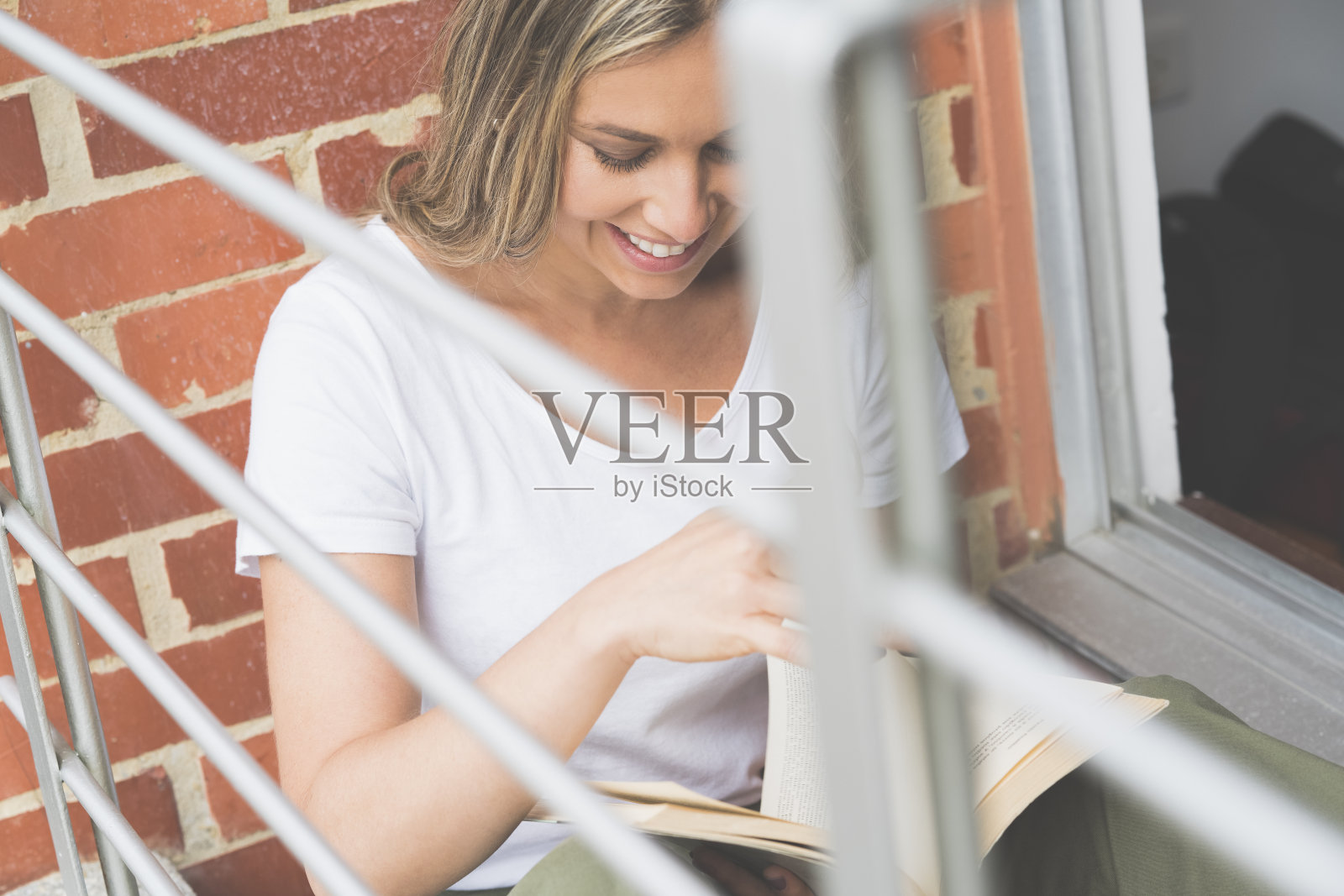 在阳台上看书的女人照片摄影图片