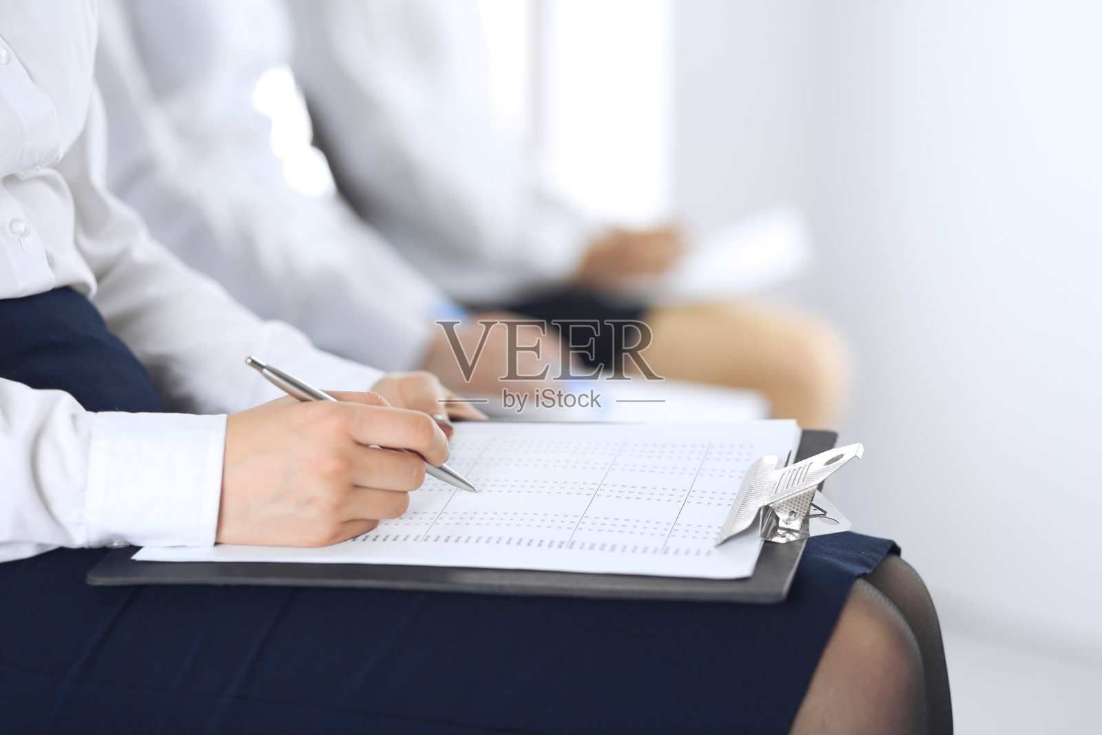 商务人士在办公室参加会议或培训，特写。女人坐在椅子上做笔记，就像排队或开会时一样。照片摄影图片