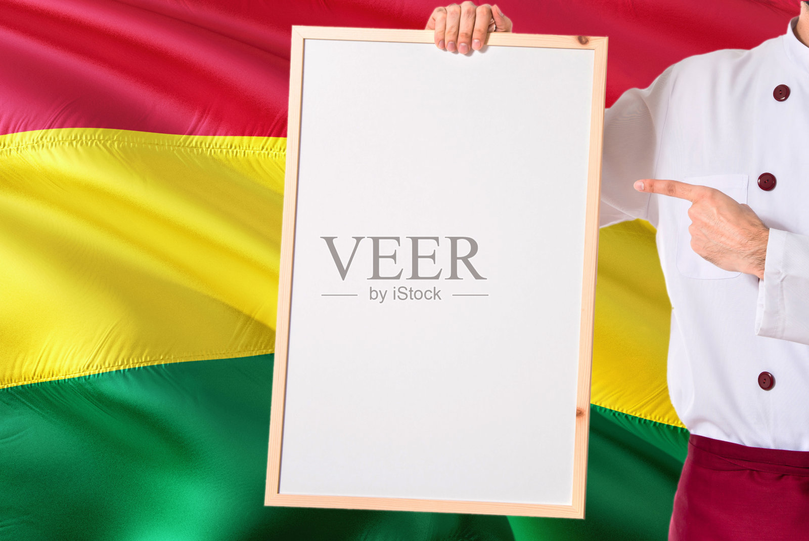 玻利维亚厨师拿着空白的玻利维亚国旗背景菜单白板。库克穿着制服指向文字空间。照片摄影图片