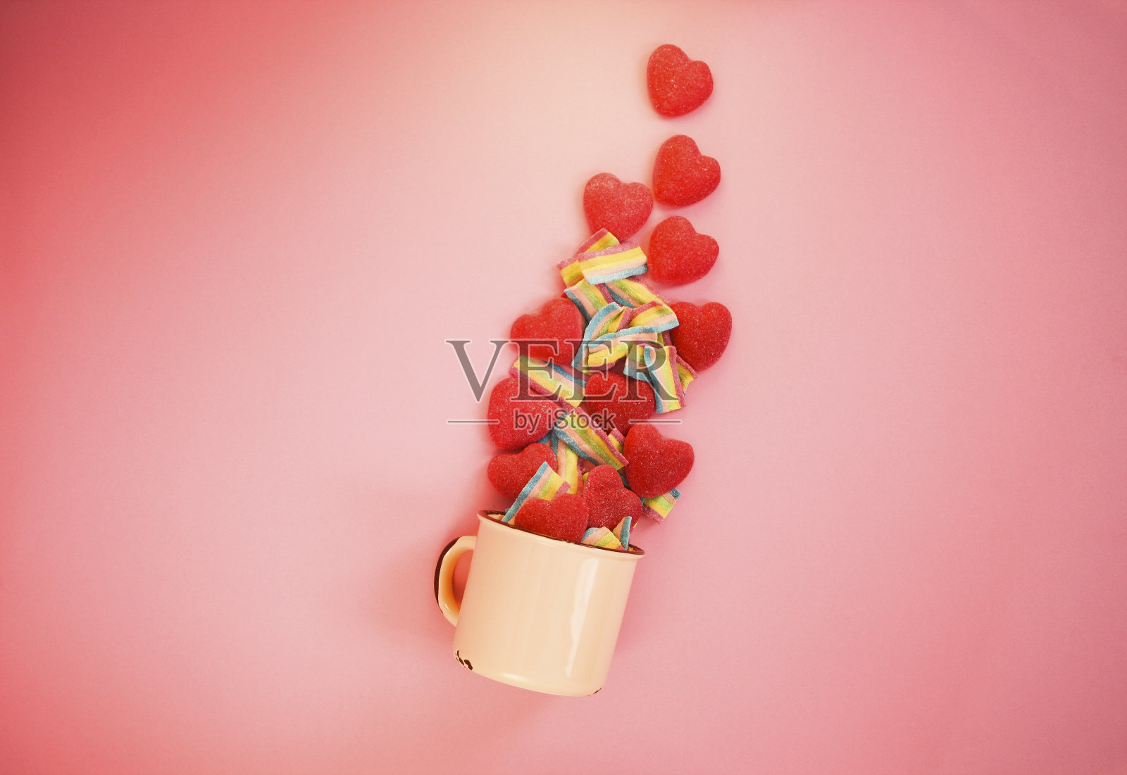 金属复古的旧杯子与红色软糖心和软糖彩虹组成。情人节概念。照片摄影图片