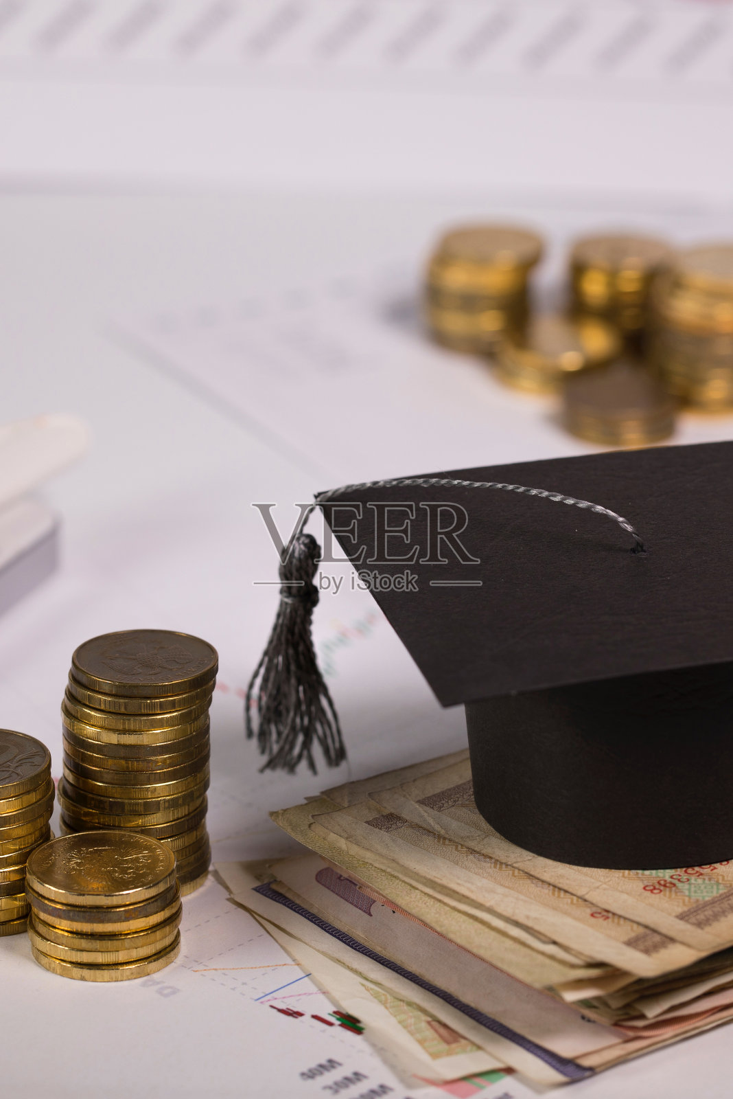 一堆钞票上的毕业帽。照片摄影图片