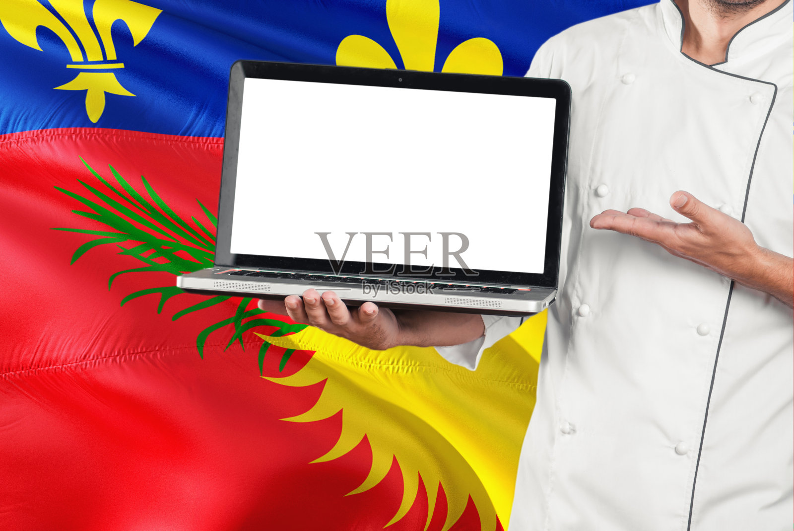 厨师拿着笔记本电脑，黑屏背景是瓜德罗普国旗。库克穿着制服，指着笔记本电脑找拷贝空间。照片摄影图片