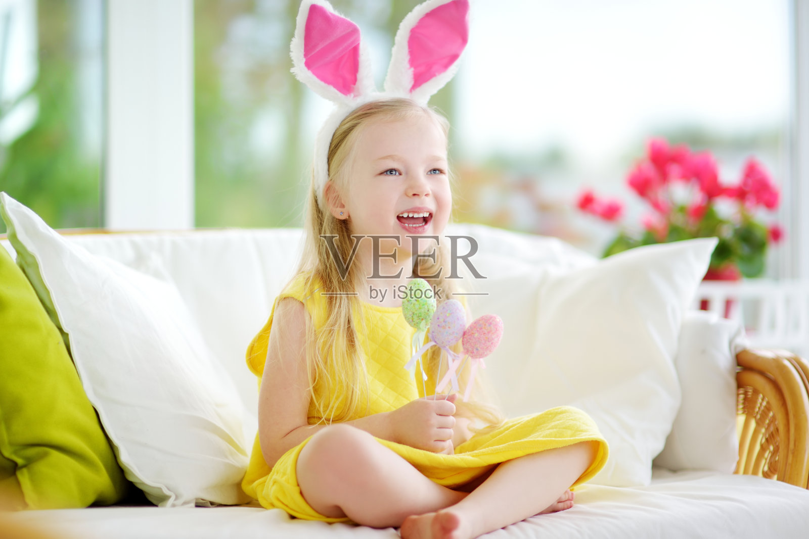 可爱的小女孩戴着兔子耳朵在复活节玩找彩蛋游戏照片摄影图片