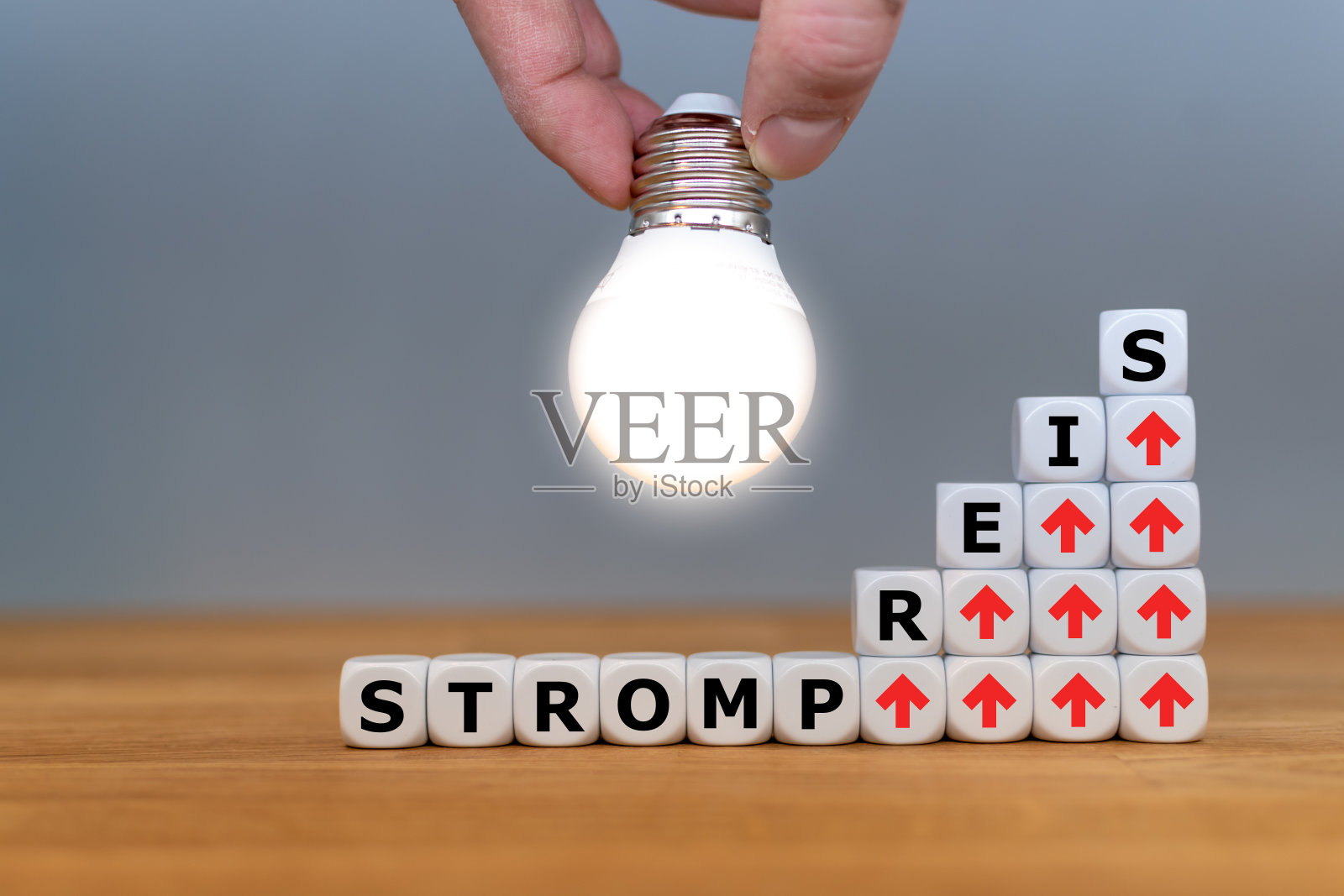 增加电价符号。在灯泡前放一个骰子，由德语单词“Strompreis”(英语中的“电量”)组成。照片摄影图片