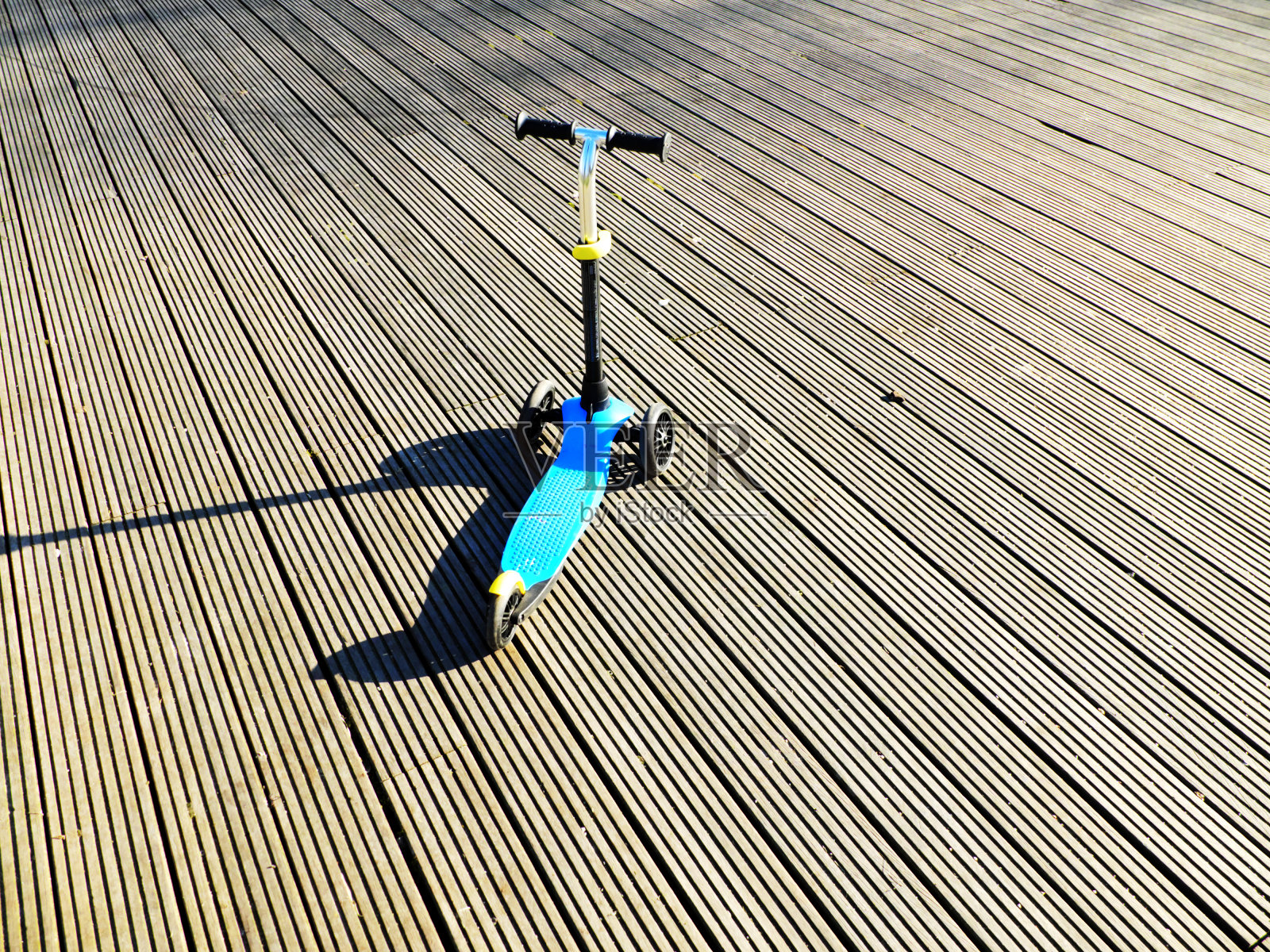 孤立的儿童踏板车上的灰色木纹在阳光明媚的日子里。照片摄影图片