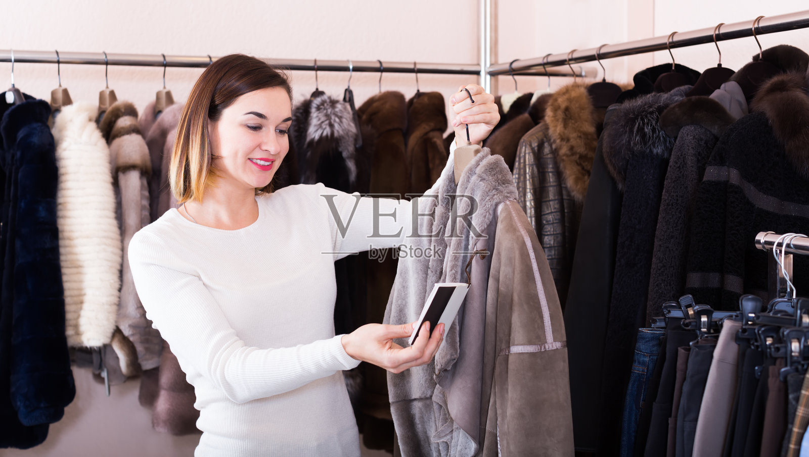 不错的女顾客正在检查一件羊皮大衣照片摄影图片